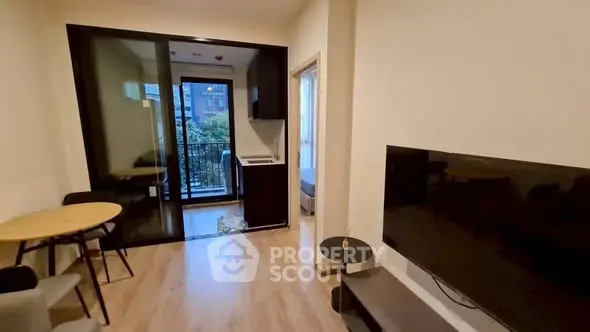Modern living room with balcony access and sleek furnishings in urban apartment.