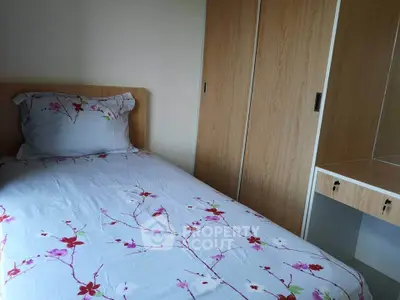 Cozy bedroom with floral bedding and built-in wooden wardrobe, perfect for a peaceful retreat.