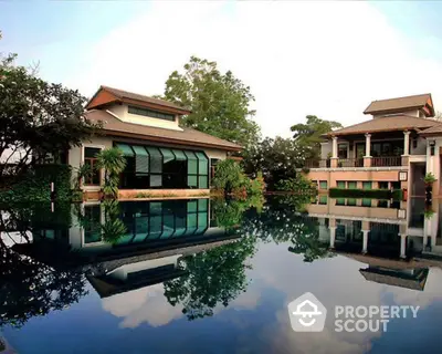 Luxurious waterfront villa with lush greenery and reflective pool, boasting serene views and modern architecture for an exclusive living experience.