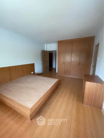 Spacious bedroom with wooden flooring and built-in wardrobe, perfect for modern living.