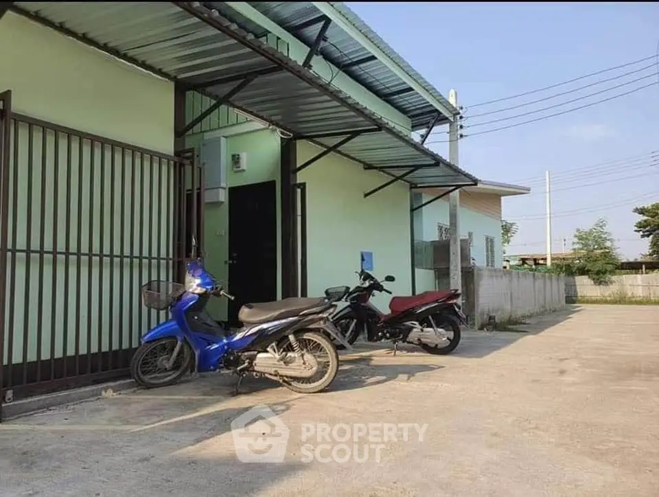 Exterior view of a residential building with motorbike parking area.