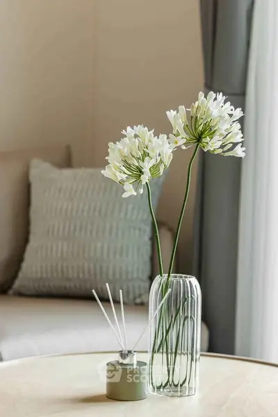Elegant living room with stylish decor and cozy ambiance, featuring a chic vase with flowers and a plush sofa.