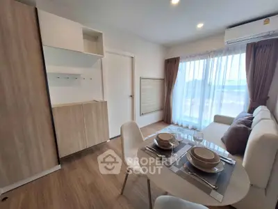 Modern living room with dining area and large window, featuring stylish furniture and natural light.