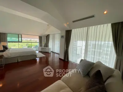 Spacious bedroom with elegant decor and large windows offering natural light and scenic views.