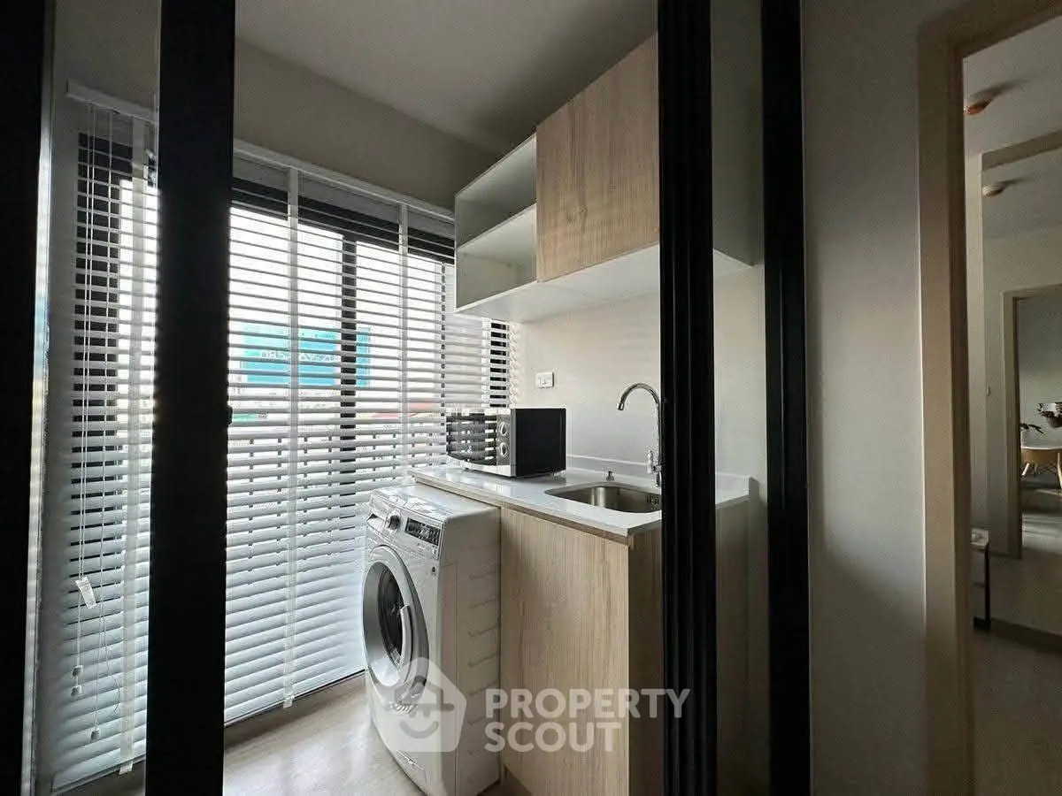Modern laundry area with washing machine and sleek cabinetry in a bright apartment.