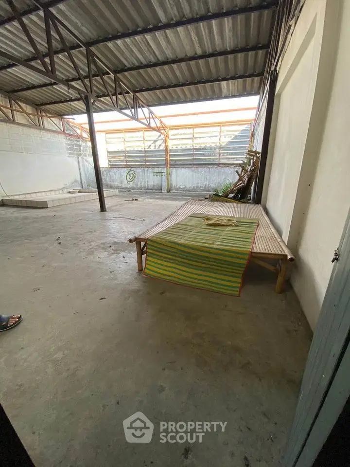 Spacious covered outdoor area with concrete flooring and bamboo furniture