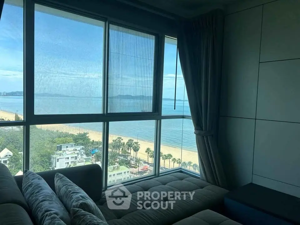 Stunning beachfront view from a modern living room with large windows.