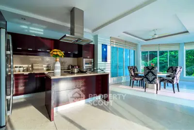 Luxurious open-layout kitchen with modern appliances and dining area overlooking lush greenery.
