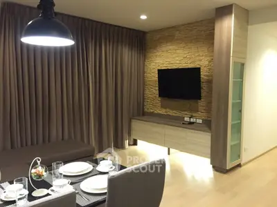 Modern living room with stylish decor and dining area, featuring a wall-mounted TV and elegant lighting.