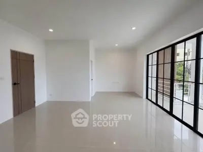 Spacious modern living room with large windows and sleek tile flooring, perfect for natural light lovers.