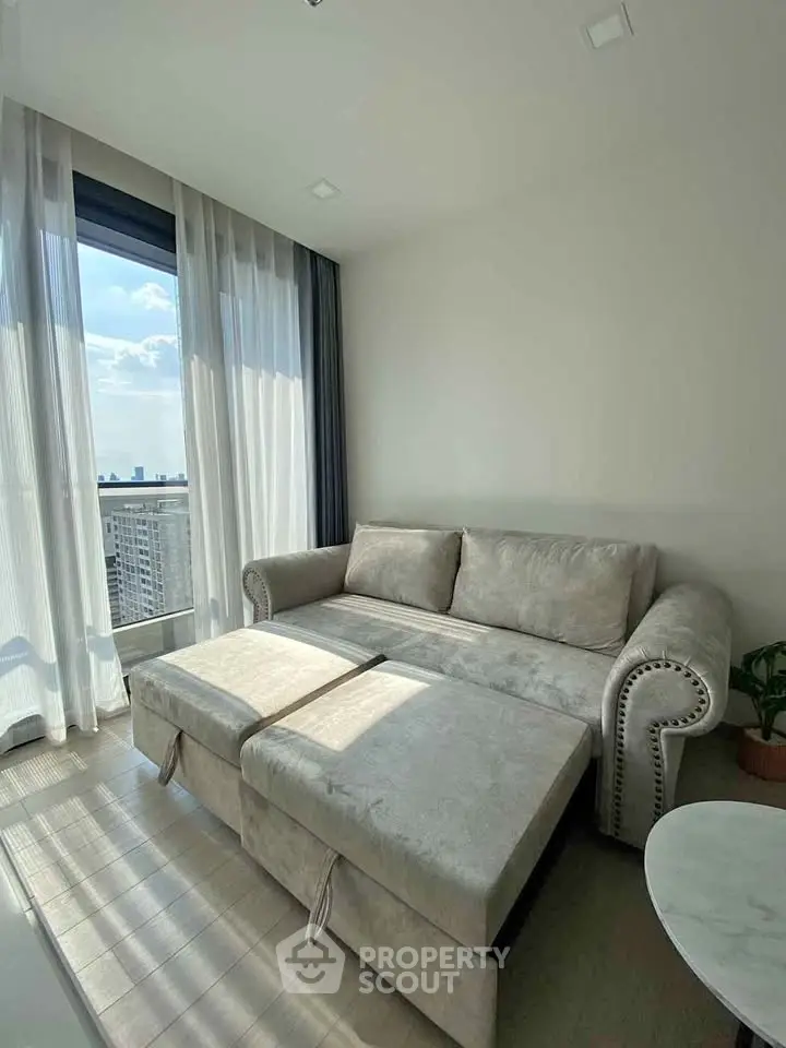 Bright living room with elegant sofa and city view through large window.