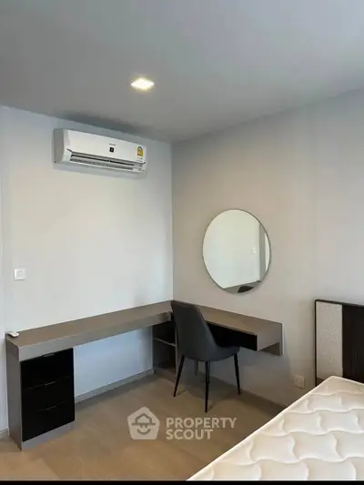 Modern bedroom with sleek desk, chair, and wall-mounted air conditioner.