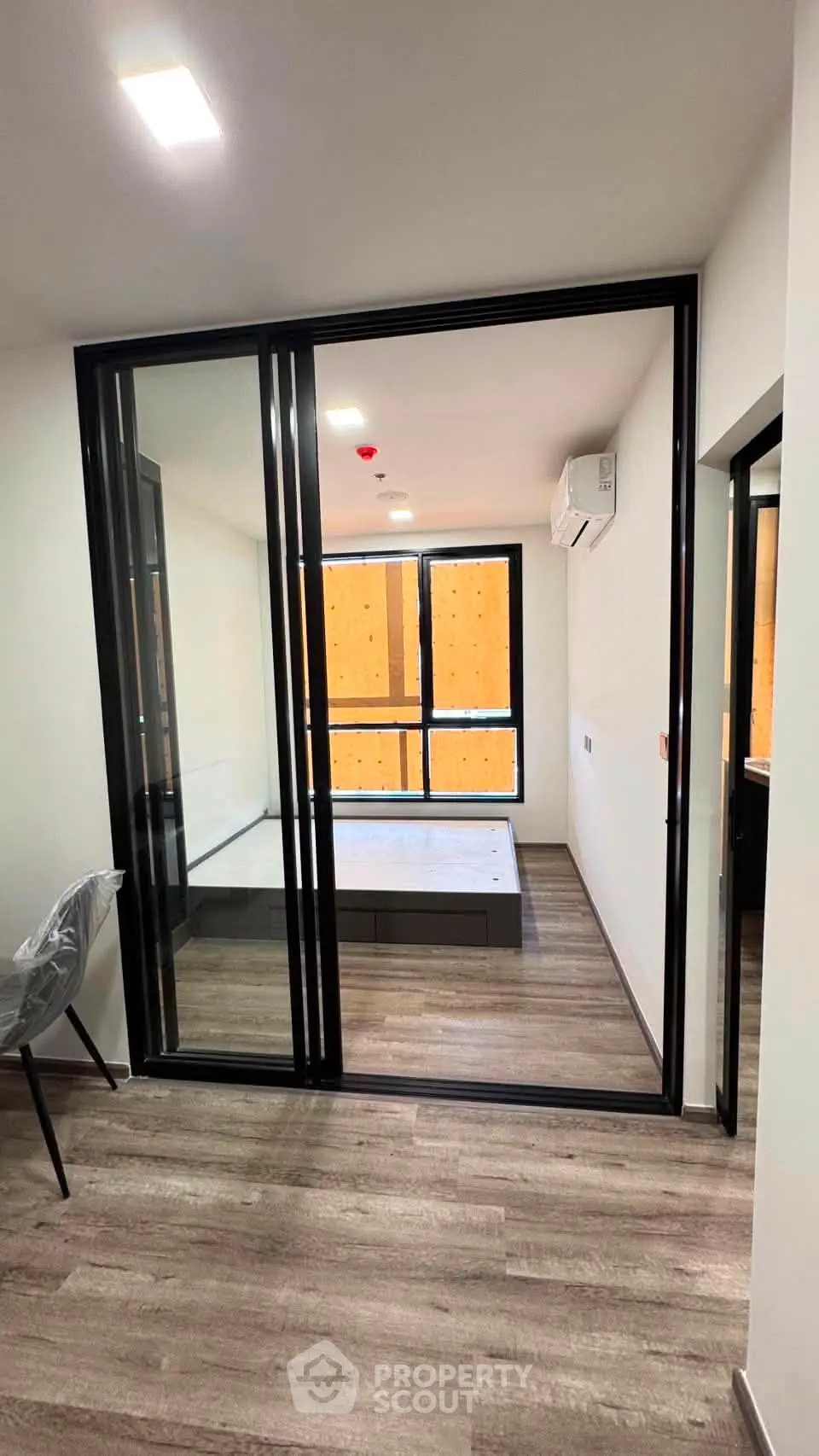 Modern apartment interior with sliding glass doors and wooden flooring, featuring a cozy bedroom and stylish decor.