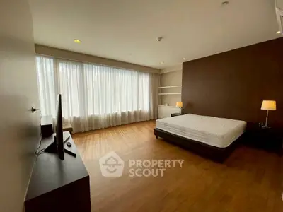 Spacious bedroom with large windows and wooden flooring, ideal for natural light lovers.