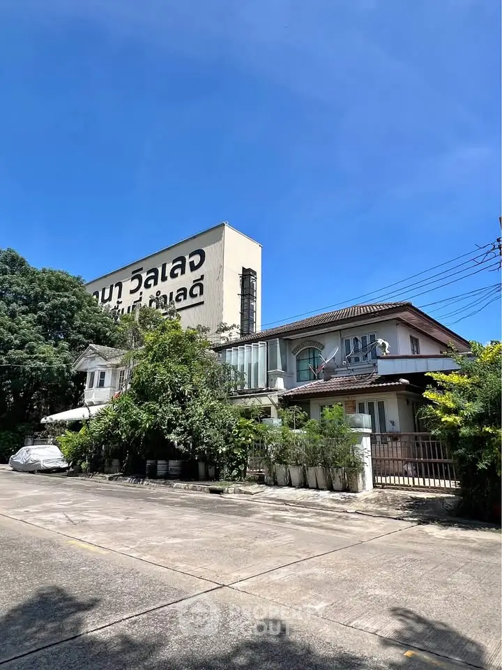 Charming suburban house with lush greenery and clear blue sky, perfect for family living.