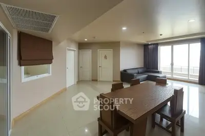 Spacious modern living room with large windows and elegant wooden dining set.