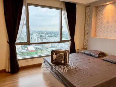Spacious bedroom with large window offering stunning city views, featuring elegant decor and natural light.