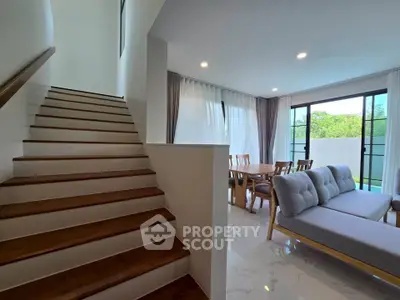 Modern living room with stylish furniture and natural light near staircase