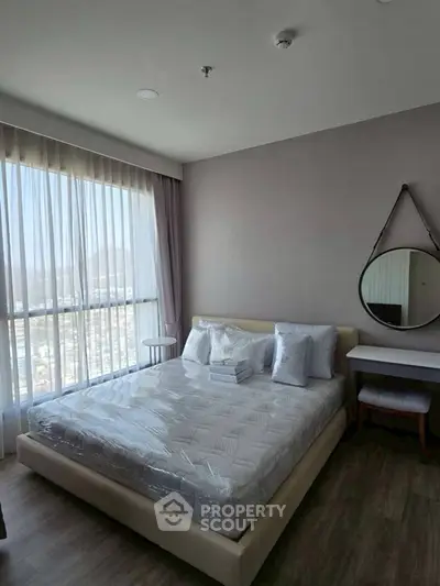 Spacious bedroom with large window offering stunning city views and modern decor.