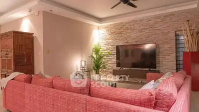 Spacious living room with modern decor and large TV, featuring a stylish red sectional sofa and stone accent wall.