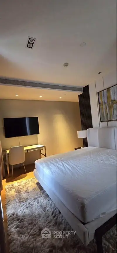 Luxurious bedroom with modern decor, plush rug, and wall-mounted TV in a stylish apartment.