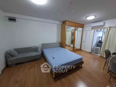 Spacious bedroom with wooden flooring, mirrored wardrobe, and modern furnishings.