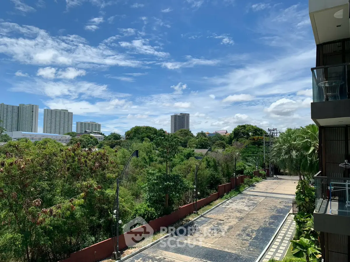 Stunning view from a modern apartment balcony overlooking lush greenery and city skyline.