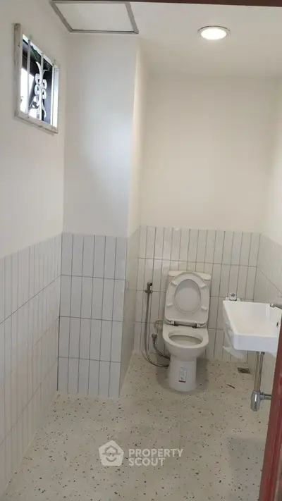 Compact bathroom with modern fixtures and tiled walls, ideal for efficient space utilization.