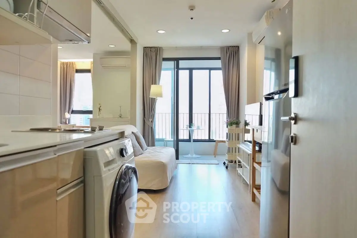 Modern apartment interior with open layout, featuring a cozy living area and kitchen with washing machine.