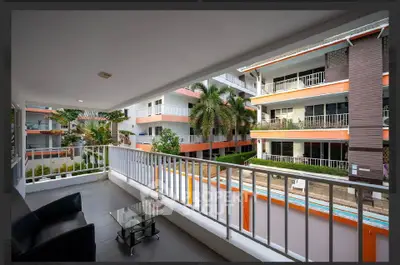 Spacious balcony with modern seating overlooking a vibrant residential complex with lush greenery.