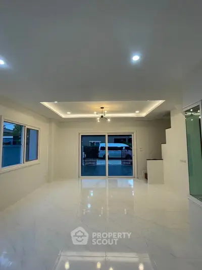 Spacious modern living room with elegant lighting and large windows, offering a bright and inviting atmosphere.
