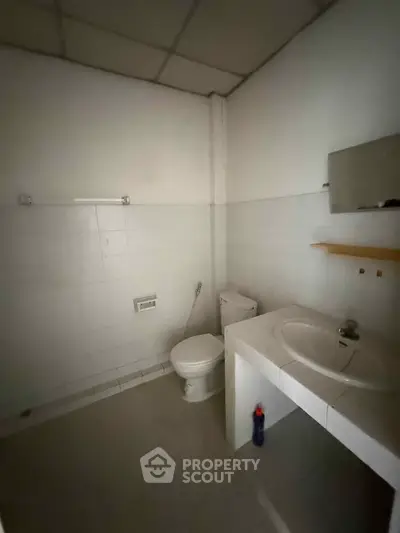 Compact bathroom with white tiles and basic fixtures, ideal for minimalist living.
