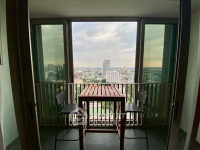 Stunning city view from a cozy balcony with seating area in a high-rise apartment.
