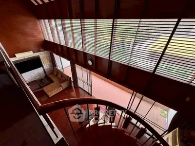 Stunning two-story living room with large windows and elegant spiral staircase