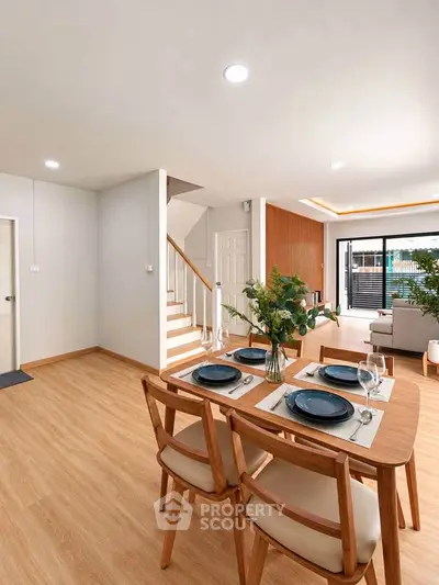 Modern dining area with wooden flooring and elegant table setting in a bright open-plan living space.