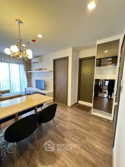 Modern living room with elegant chandelier and stylish furniture in a cozy apartment setting.