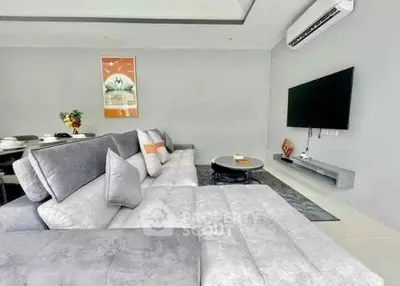 Modern living room with sleek grey sofa and wall-mounted TV, perfect for relaxation and entertainment.