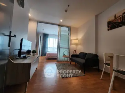 Modern apartment with cozy living room and bedroom view, featuring sleek furniture and warm lighting.