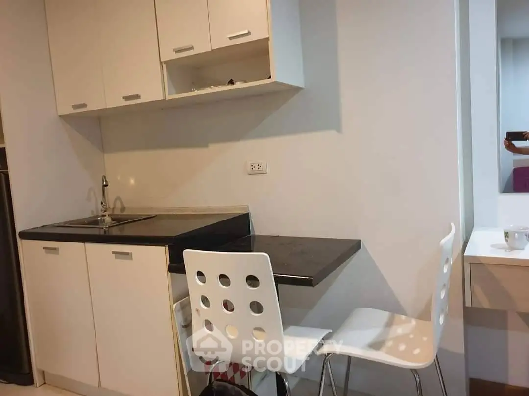 Modern compact kitchen with sleek white cabinets and cozy dining area.