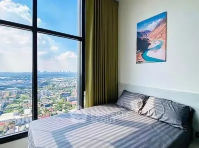 Cozy bedroom with stunning city view from large window, featuring modern decor and natural light.