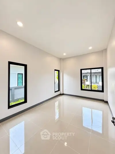 Spacious unfurnished room with large windows and glossy tiled floor, perfect for customization.