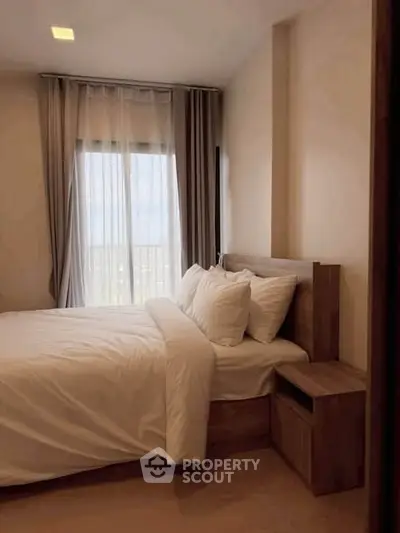 Cozy bedroom with modern wooden furniture and large window offering natural light.
