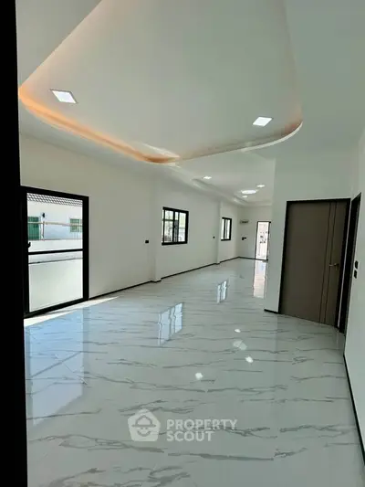 Spacious modern living room with elegant ceiling design and marble flooring.