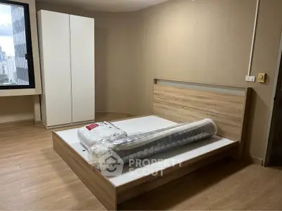 Modern bedroom with wooden flooring and city view, featuring a new bed and wardrobe.