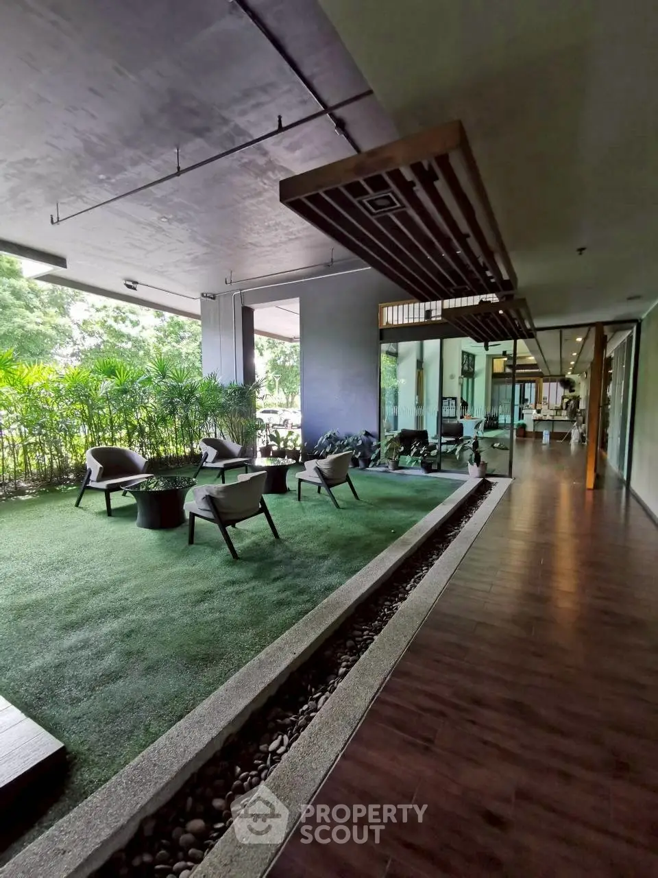 Modern building entrance with lush greenery and stylish seating area.