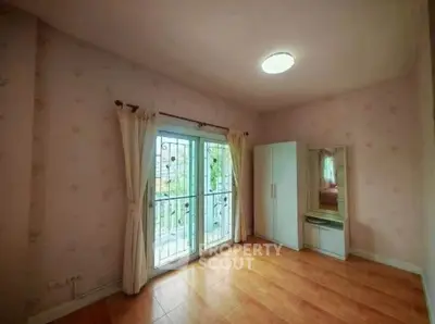 Spacious bedroom with large window and wardrobe, ideal for cozy living.
