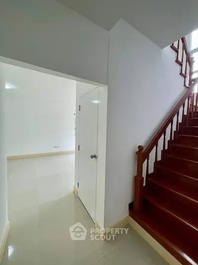 Spacious interior with elegant wooden staircase and modern tile flooring