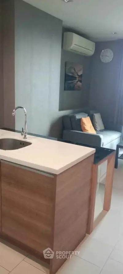 Modern kitchen with open layout and cozy living area, featuring sleek countertops and stylish decor.