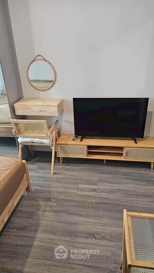 Modern living room with wooden furniture and flat-screen TV, featuring a cozy and minimalist design.