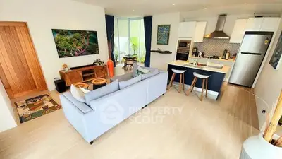 Modern open-layout living room and kitchen with stylish decor and natural light.